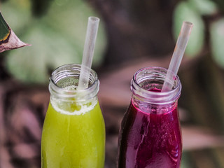 red and green healthy beetroot fruit and vegetable juice in a glass bottle with a straw and...