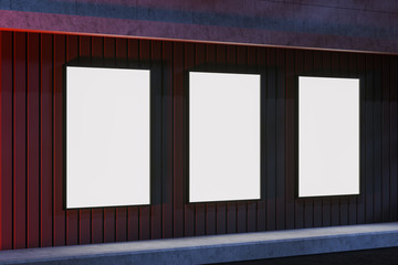 Three blank billboards on building wall at night
