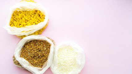 Quarantine food supplies. Stocks of products. A crisis. Food delivery, donation. Macaroni, rice and buckwheat in bags on a pink background. Copy space. Place for text.