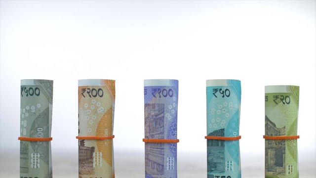 Tilt shot of various bundles of colorful Indian paper currency - finance concept. Rolls of new 500 rupees  200 rupees  100 rupees  50 rupees  and 20 rupees notes placed on a wooden table - white ba...