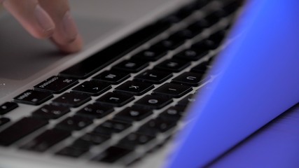 Close-up female fingers typing on laptop keyboard and touchpad. Man works at home of computer, close-up. Side view. Stay home. Technology in everyday life. Quarantine
