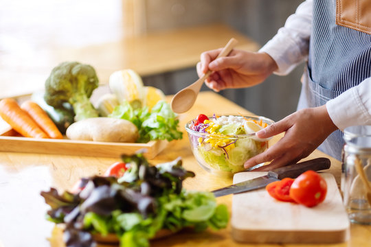 Closeup image of a female chef cooking and holding a bowl of fresh mixed vegetables salad to eat in kitchen