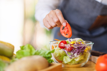 Closeup image of a female chef cooking a fresh mixed vegetables salad in kitchen