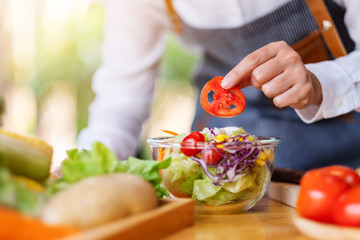 Closeup image of a female chef cooking a fresh mixed vegetables salad in kitchen