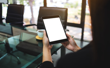 Mockup image of businesswoman holding black tablet pc with blank white screen in the office
