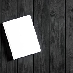 Mockup of closed blank square book at white textured paper