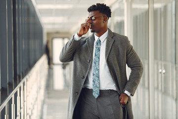 Black man in gray coat. Businessman working in a office. Guy at the lobby.