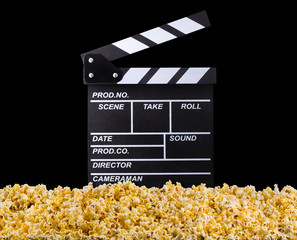 Flying popcorn and film clapper board isolated on black background