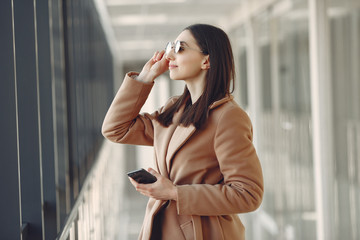 Girl in the office. Woman in a brown coat. Lady use the phone.