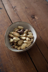  brazil nuts in a rustic ceramic bowl on wooden background