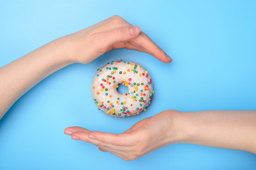 Perfect food creating concept. Photo of tasty donut with colorful sprinkles and two hands making roof catching the flying object isolated over pastel rerto pattern background