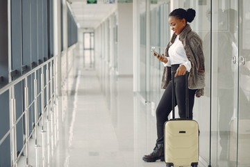 Black woman at the airport. Girl with suitcase. Lady in a white shirt.