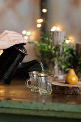 tea is poured into a turkish cup on the background of lights