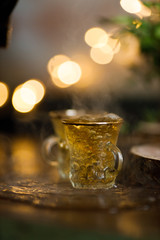 tea is poured into a turkish cup on the background of lights
