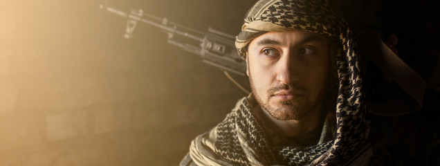 Arab male soldier in a headdress from the national keffiyeh with a weapon in his hands man with a gun on a black background - obrazy, fototapety, plakaty