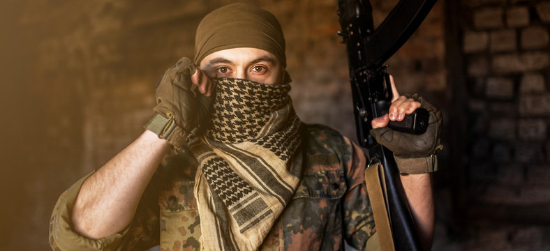 Arab male soldier in a headdress from the national keffiyeh with a weapon in his hands man with a gun on a black background