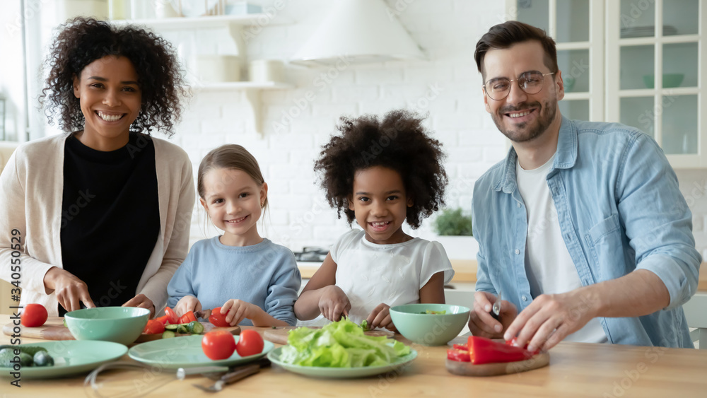 Wall mural portrait of happy young multiracial family with little children cook together in modern renovated ki