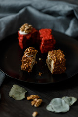 a piece of sliced cupcake in colored chocolate glaze served on a black plate a stylish composition with walnuts
