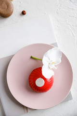 red mousse cake on a pink plate with orchid