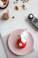 red mousse cake on a pink plate with orchid and light meter