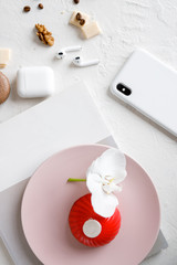 red mousse cake on a pink plate with orchid and smartphone