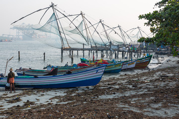 Fototapeta premium Kochi, Kerala - December 30, 2019: Fishing boats parked next to the chinese fishing nets in fort kochi, kerala india