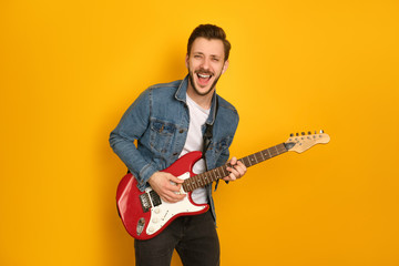A portrait of sassy handsome man playing electric guitar, laughing pleased