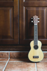 Fototapeta premium Standing ukulele leaning against wooden cabinet 