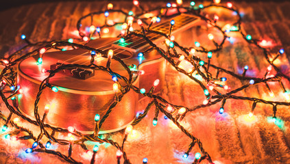 Ukulele on a bed wrapped in colored lights