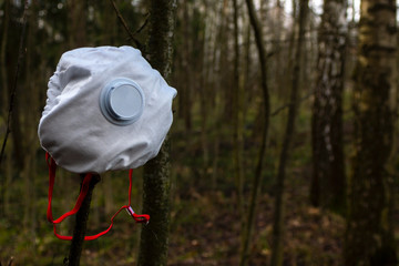 Closeup white respirator on a tree branch in the forest.