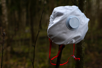 Closeup white respirator on a tree branch in the forest.