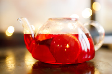 Hibiscus tea in transparent teapot on table. Herbal tea rosella, karkade or red sorrel are fruit tea.