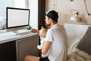 Father Working From Home On Computer With Baby Son