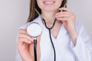 Listening to lungs concept. Cropped close up photo of young inter girl using phonendoscope to listen to her patient isolated over grey background