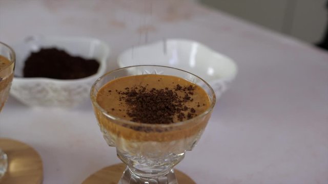 Closeup of cocoa grains falling on delicious foamy dalgona coffee, slow motion