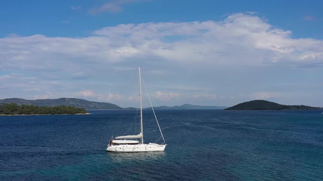 Sailboat navigating over Blue Sea - Aerial Drone Circle around View