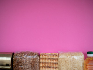 Can, buckwheat, biscuits, rice, oil on pink background, top view with copy space