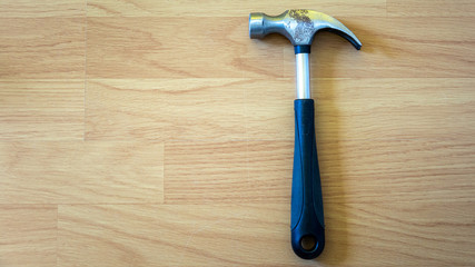 Hammer placed on wooden floor signifying wood work with copy space for your text