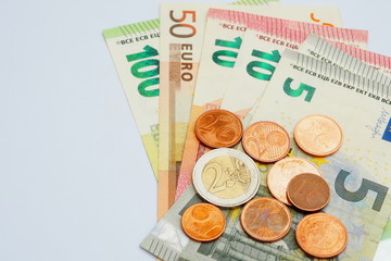 Top view of several Euro banknotes and coins on white background for money spending in Europe and payment purpose. Financial planning and savings concept