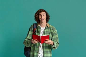 Back to school. Happy student with open notebook and backpack on turquoise background