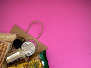 Craft package with food supplies on pink background, top view with copy space