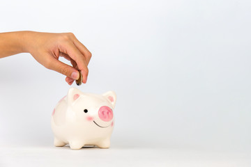Hand putting coin in piggy bank on white background, Saving concepts