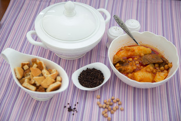 Kufta bozbash . A bowl of white ceramic salt and pepper. Dried bread crumbs in a bowl, black pepper . Bowl of Bozbash - delicious Azerbaijan national soup on the table with white flowers .
