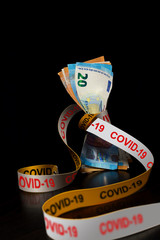 Banknotes tightened by a ribbon with Covid-19 written on black for the concept of financial crisis caused by the Coronavirus pandemic