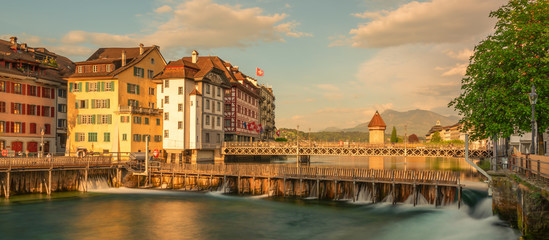 Naklejka premium Panoramic evening view of popular tourist attraction with historic Chapel bridge. Spectacular spring cityscape of Lucerne. Stunning outdoor view of Switzerland, Europe. Traveling concept background.