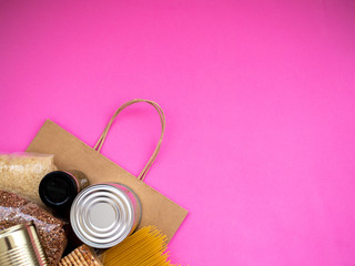 Craft package with food supplies on pink background, top view with copy space