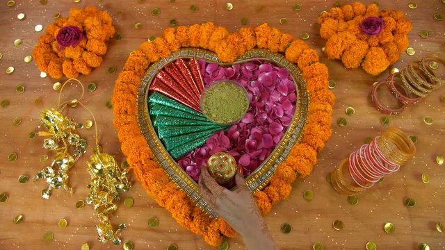 Hands of a young woman placing a designer case of traditional Indian tilak indoor - Wedding Rituals . Top view shot of beautifully decorated floral platform with sindoor box  mehndi  mehndi cones  ...