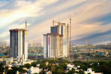 Aerial shot of under construction building with multiple floors and crane at the top standing out in the countryside. Shows the rapid development of skyscrapers even in the most rural areas with the