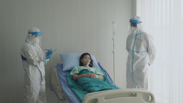 doctor in personal protective equipment or ppe treating patient with covid-19 or coronavirus infection in isolation unit in hospital during pandemic. medical and healthcare concept