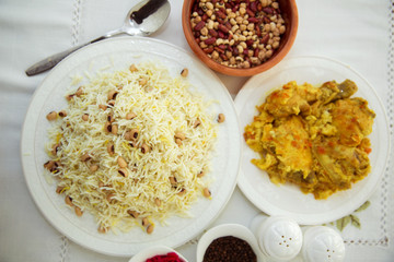 Khan pilaf in a pita . Dry beans on top of pilaf . Dry beans in a brown bowl . Chicken curry on the white plate . red cabbage sauerkraut and black pepper in a bowl . Shah pilaf on the white plate.